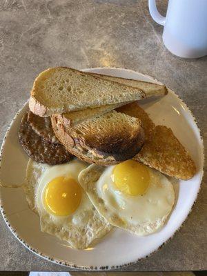 Two eggs sausage patties and hash browns with sourdough toasts