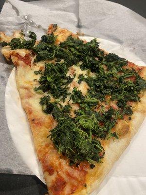 DRY, COLD Spinach thrown in a pile on top of a slice of old cheese pizza.