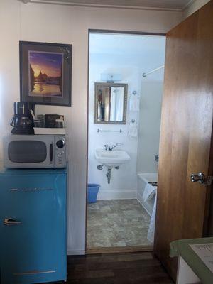 Looking toward the bathroom with mini fridge, microwave, and coffee maker to left of bathroom door.