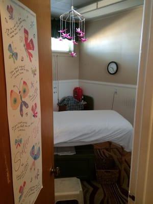 View from Hallway through opened door of Treatment table, step stool, laughter quote poster