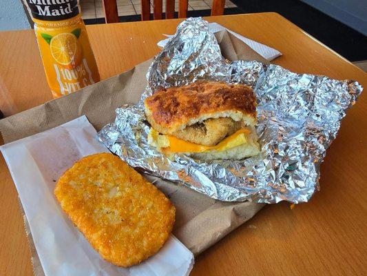 Breakfast chicken egg and cheese biscuit with hashbrowns and an orange juice