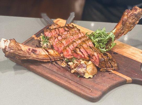 Grilled tomahawk steak over duck confit potatoes, mushrooms,wilted arugula &balsamic glaze