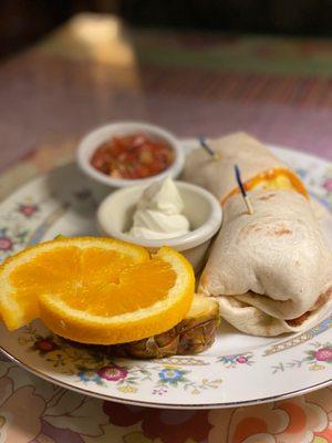 Egg, cheddar, and bacon burrito with fresh fruit.