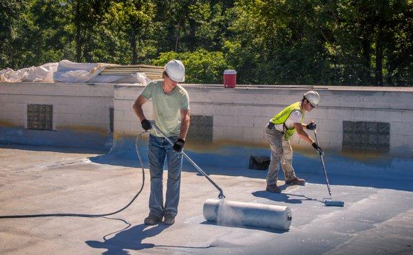 Capital Coating workers apply a coating on a commercial roof