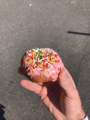 Cake donut with pink icing and sprinkles