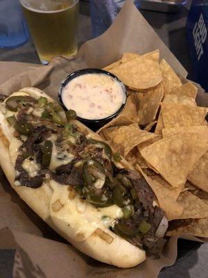 Prime rib philly with jalapeños and chips and queso.