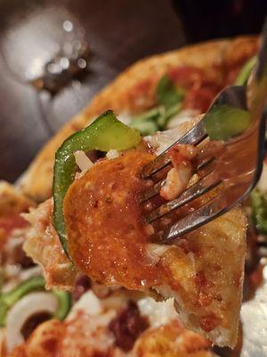 Close-up of a fork holding a piece of the Pizza Suprema.