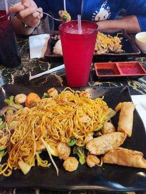 My yakisoba with broccoli, bean sprouts, carrots, onions, celery, seafood, and tofu with spring rolls and gyoza and a glass of lemonade.