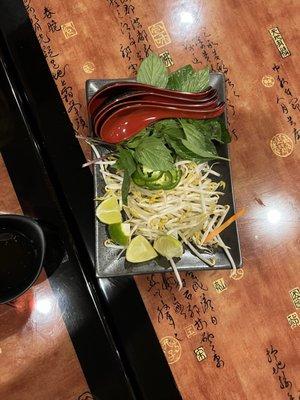 The fixings for pho - sprouts, lime, basil, mint