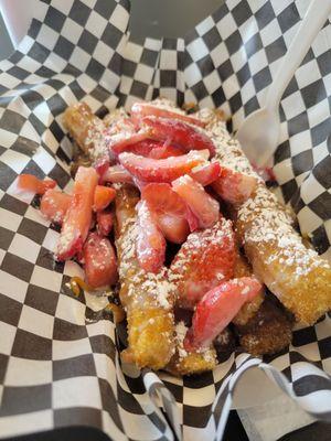 Churros topped with strawberries, condensed milk, and a milky caramel sauce