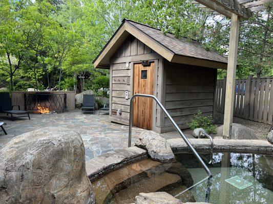 View of the sauna, fire pit, hot tub, and lounge chairs