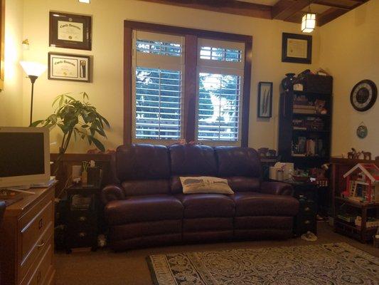 Leather couch with side tables, bookshelf, and window