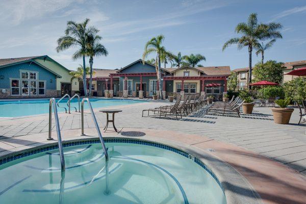 Swimming pool and spa surrounded by lounge chairs.