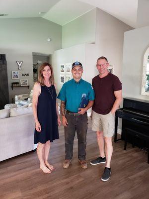 An Elite Rooter technician standing with satisfied homeowners after delivering exceptional plumbing service.