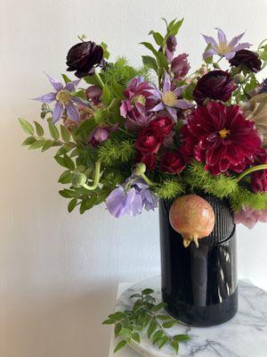 We love to incorporate unexpected elements into our florals.  Burgundy dahlias and ranunculus frame fresh pomegranate.