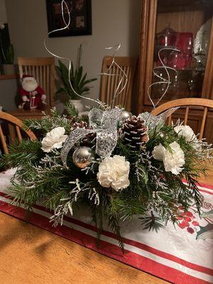 Winter bouquet of seasonal foliage, white carnations, pinecones, glass balls and sparkling twigs.