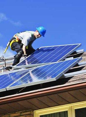 One of Unified Solar And Roofing technicians installaing solar panels on the roof of one of our customers residential homes