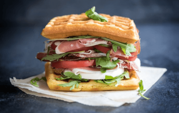 Toasted waffle sandwich served with tomatoes, lettuce, ham, and cheese