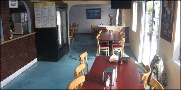 The un-crowded dining room of Maron's Mexican Restaurant, with the kitchen, and the beverage cooler to the left of the photo.