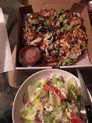 Small veggie pizza with extra broccoli and sausage in a side Greek salad