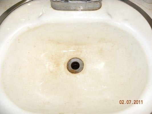 Before picture of a bathroom sink with rust and hard water deposits