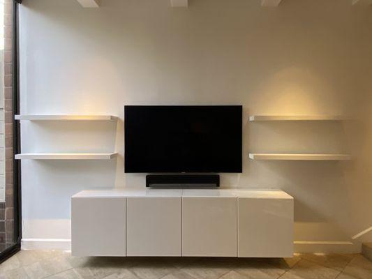 A simplistic, yet modern look for the living room. Glossed stacked floating shelves on both side of the mounted Sony tv and Sonos soundbar.