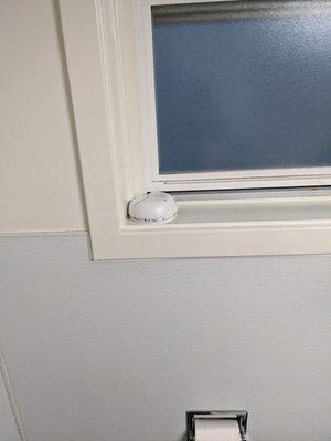 Smoke alarm sitting on bathroom window sill.