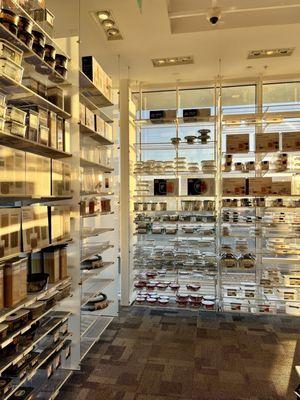 Clear and translucent containers line the glass shelves and curtain wall on a sunny winter day with corporeal light during the golden hour.