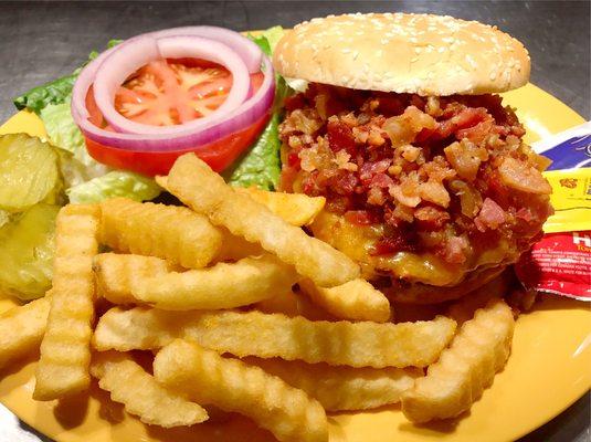 Bacon Cheeseburger with fries served with lettuce, tomato, onion, pickles, mayonnaise, mustard, and ketchup on the side.