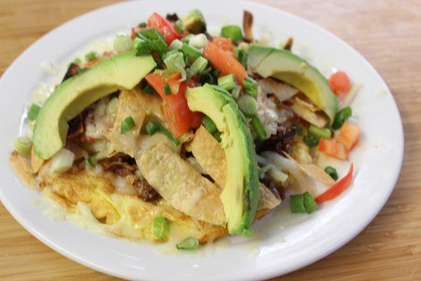 Carnita Ranchera - House Specialty: Open-faced omelet topped w/hash browns, tomatoes, fried corn chips, shredded brisket, cheese & garnish.