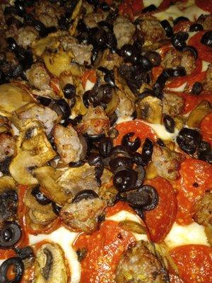 Up close pepperoni,  sausage,  mushroom and black olive pizza.