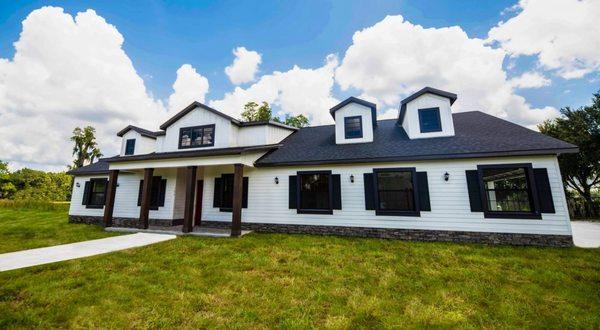 This one story custom designed home built by Rotunda Homes features dormers, Hardie-Board, stone, and wooden entry posts.