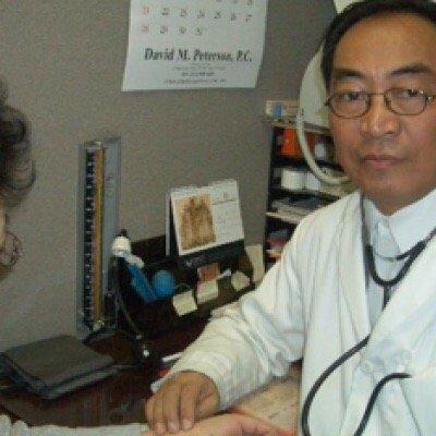 Dr. Yang taking a patient's pulse while smiling for the camera!