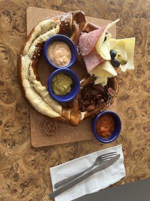 The pretzel charcuterie board with pecans, olives, a hot pretzel, meats, cheeses, and three very tasty sauces.