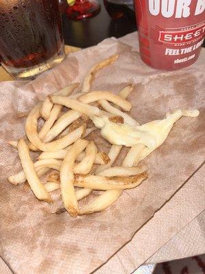 Cup of fries with a glob of unwanted cheese in the bottom.