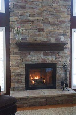 New stone fireplace with wooden mantle and custom doors