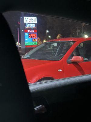 Employee sitting in his car on the phone. Gas station is clearly open for business.