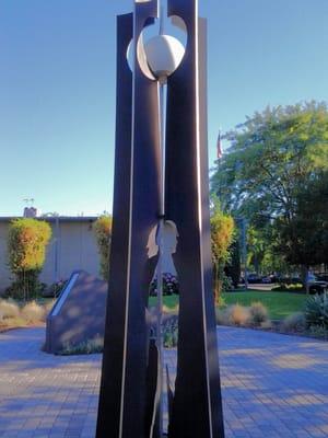 Tall sculpture with profile cutouts of soldiers near the memorials