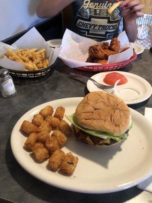 Cheddar bacon burger with tots and buffalo wings with fries.