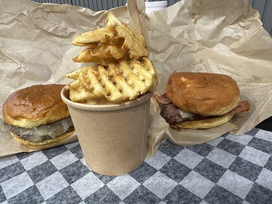 Smash cheese burger with waffle fries and a bacon smash burger with cheese.