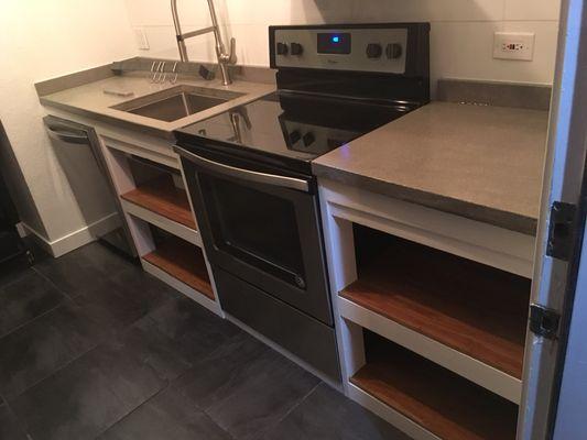 Cabinetry built with 2x4 lumber with concrete counters made from scratch and pre-finished red oak hardwood shelves.