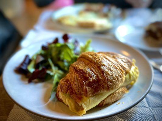 Buttered croissant with egg and ham with salad