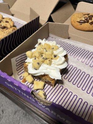 Brownie topped with icing and cookie dough pieces.