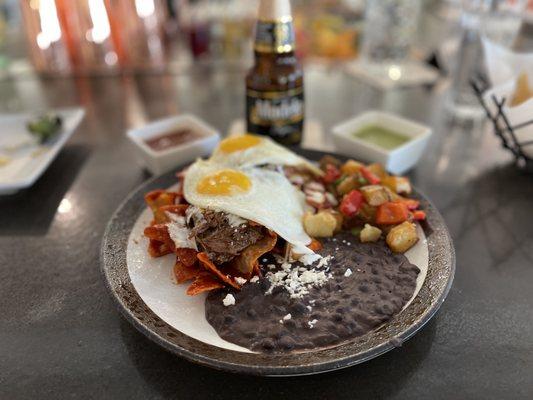 Birriaquiles - homemade tortilla strips, molcajete-consomme broth & short rib meat topped with crema & queso fresco. We added eggs.