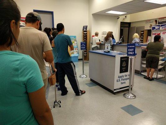 Long line and only one person working the counter. The 2nd worker is standing behind a counter that says "next station please".