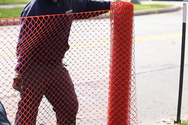 Installing orange fencing in Chicago by United Rent-A-Fence temporary construction fencing