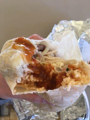 Insides of the carne Asada burrito - rice, pico de gallo, sour cream, carne Asada - topped with red hot sauce.