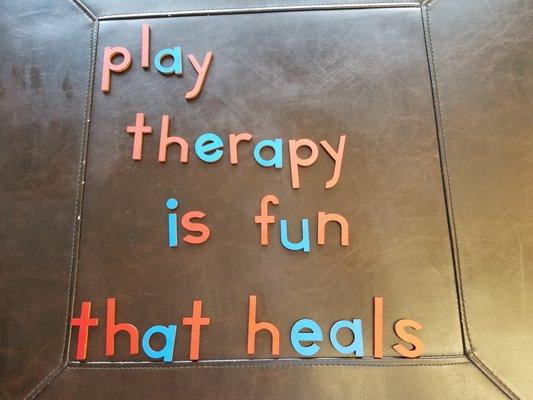 Lowercase letters in red and blue that spell out "play therapy is fun that heals"