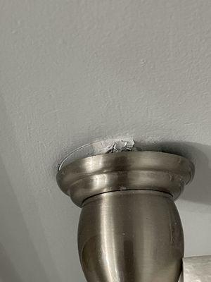 Toilet paper holder pulling out of the wall due to latex paint allowing moisture penetration.