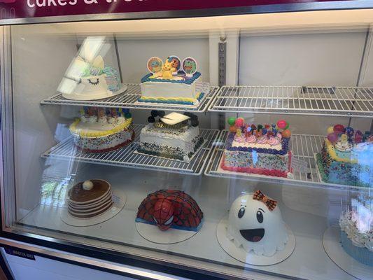 A display of a variety of creative cakes for sale.